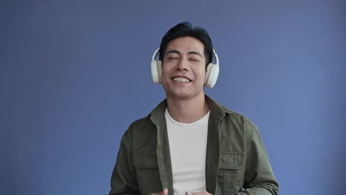 Asian Millennial Dancing, Wearing Headphones on Blue Background
