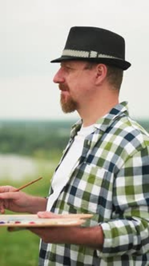 Man Painting in Field with Paintbrush and Palette