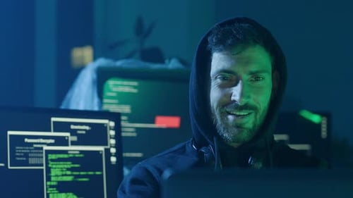 A Focused Hacker Engaged in Work Across Multiple Monitors Within a Tech Environment