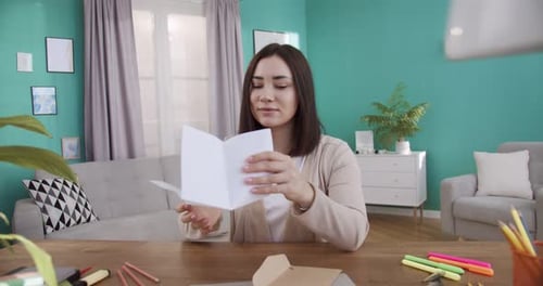 Young Woman Reads Letter at Her Home Desk