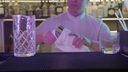 Barman Polishing Cocktail Shaker at Night