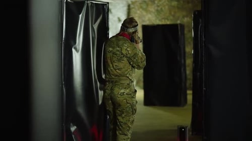 Military training exercise highlighting tactical maneuvers in an indoor arena with various obstacles