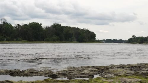 Das Wasser eines Flusses, der frei fließt, mit Bäumen am gegenüberliegenden Ufer