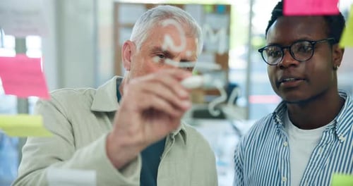 Men Brainstorming Together Writing on Glass in Office