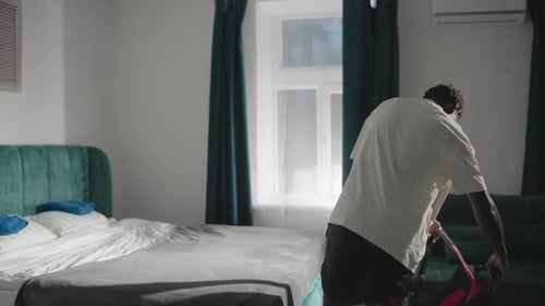 Person Holding Bag in Modern Bedroom with Green Velvet Headboard and Soft Lighting