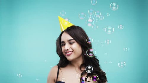 Party hat, dancing and bubbles with woman on blue background to celebrate birthday