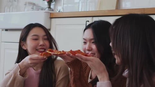 Three Asian friends enjoying pepperoni pizza together