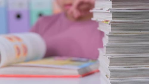 Child Reads Books at Desk in Bright Room