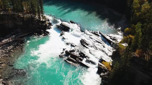 aerial zoom out shot of Rearguard Falls drone flying past trees towards the waterfalls on a sunny da