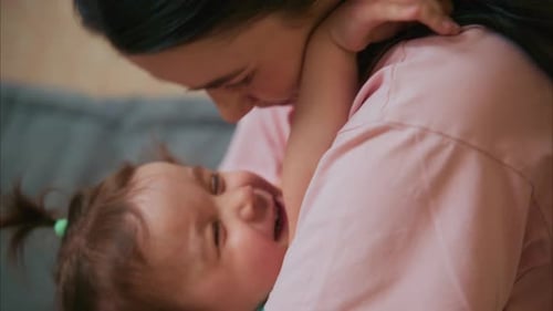 Loving Woman Hugs Child Tenderly Indoors