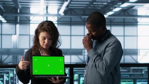 Woman Presenting Laptop with Green Screen to Colleague