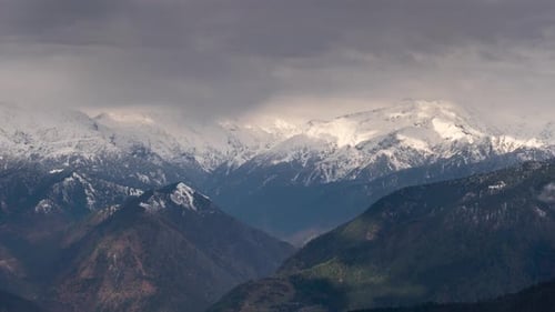 Snowy Mountains and Rugged Terrain Under Cloudy Sky
