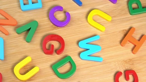 Multicolored letters rotate on a wooden background. The concept of learning, school or college