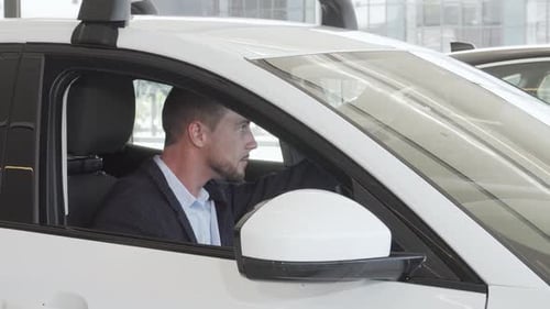 Young Man Smiling in a Car in Showroom