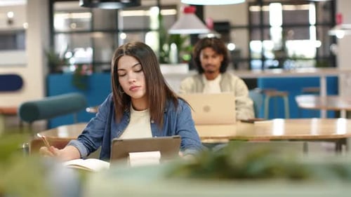 African American classmates studying in coworking space, woman taking notes from tablet for exam