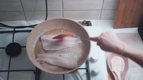 Woman pirien fish in a pan at home. close-up. homemade fish grill
