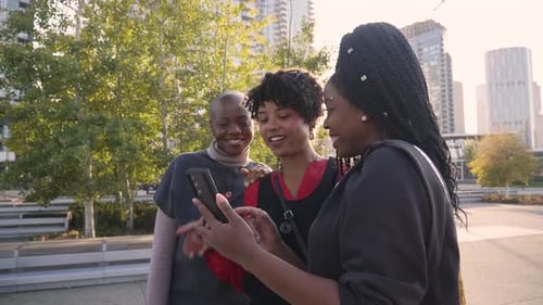 Happy Women Friends Using Smart Phone in City Park 3034 Years