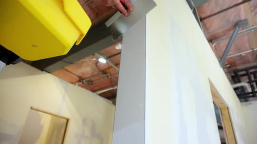 Construction Worker Applies Joint Compound to Drywall End Using a Metal Spatulas Worker Smoothing