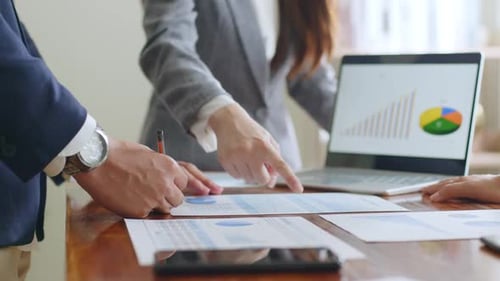 Multicultural business professionals discuss project plans and financial results in office,