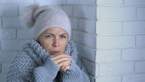 Woman Shivering in Hat and Scarf Indoors
