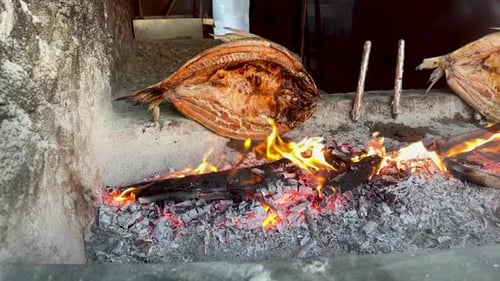 Bream fish in an Iraqi restaurant butterflied and grilling on a fire in slow motion