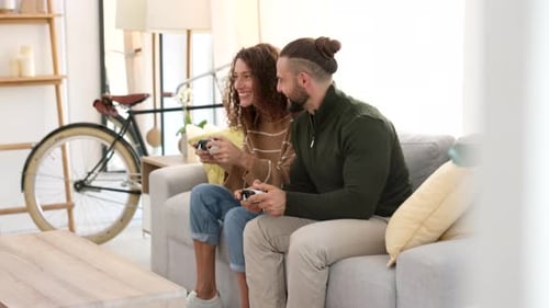 Gamer, video game and happy couple arcade gaming playing a fun competition together in an apartment