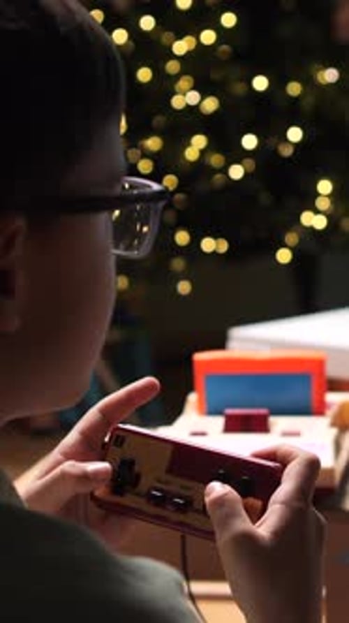 Vídeo vertical: Niño jugando videojuegos retro en casa durante las vacaciones de Navidad