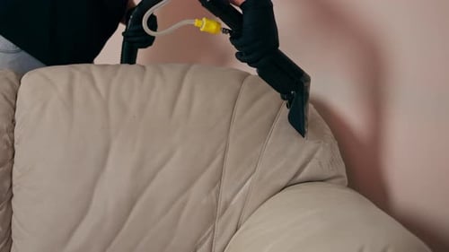 Limpieza profesional de cerca en un limpiador de apartamentos moja un sofá textil antes de lavarlo