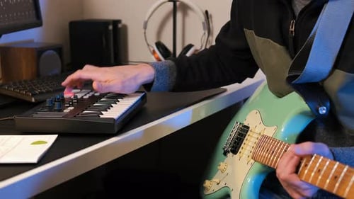 Man Plays MIDI Keyboard with Guitar in Studio