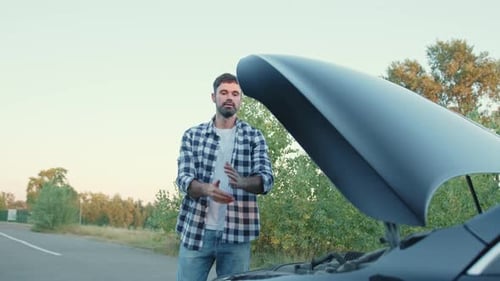 Young Man Leaning on the Hood of a Broken Car Slow Motion