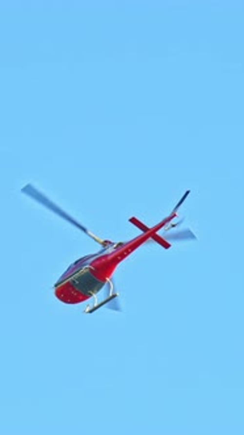 Red Helicopter Flying Against Blue Sky