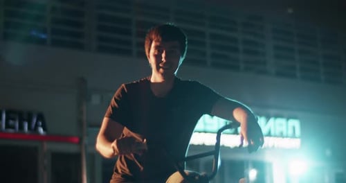 Smiling Sportsman Sitting on BMX on Street in Evening
