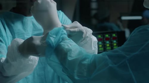 Assistentin hilft Chirurgen beim Anziehen von Handschuhen im Operationssaal