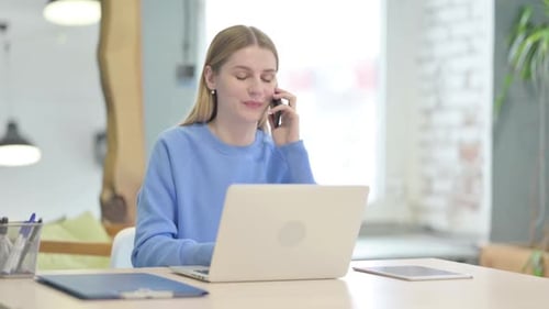 Young Woman Working and Talking on Phone in Office