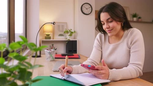 Woman Working at Desk with Phone and Notebook