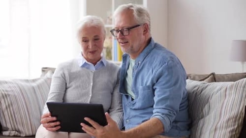 Senior couple using tablet on sofa together indoors
