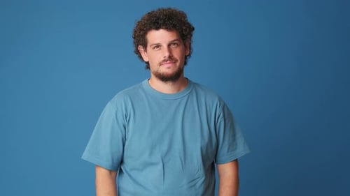 Happy man showing thumbs up gesture isolated on blue background in studio