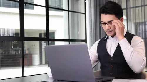 Focused Man Works on Laptop in Modern Office