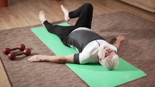 Senior Man Stretching on Exercise Mat at Home