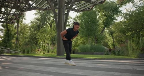 Man Stretching in City Park on Sunny Day