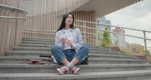 Woman Sitting on Steps Holding Water Bottle