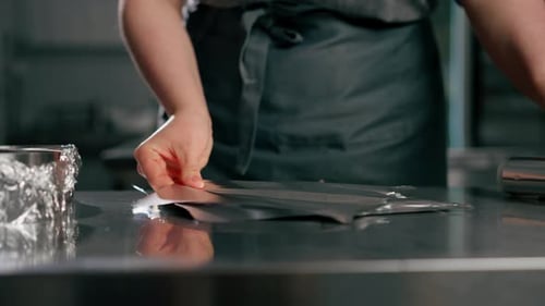 Close Up Hands Baker in Professional Kitchen Wraps the Pans with Foil Before Pouring the Dough Onto