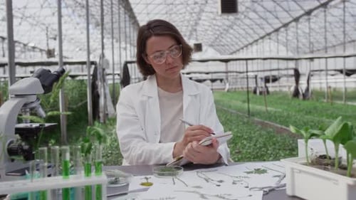 Young Woman Writes in Greenhouse Lab