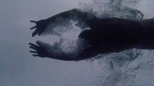 Man swimming butterfly underwater view from bottom of pool pointing up