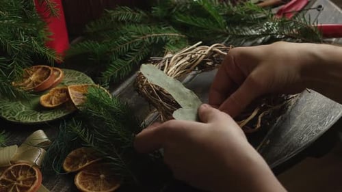 Hands Crafting Christmas Wreath With Pine Sprigs