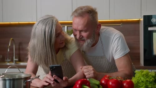 Cheerful Middle Aged Couple Laughing in the Kitchen