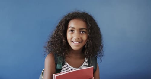 Smiling Child Ready for School with Book and Backpack