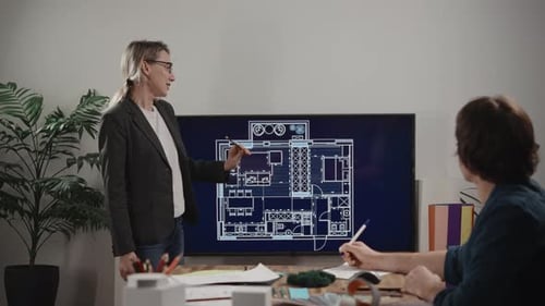 A Woman is Giving a Presentation of an Architectural Project On the Large Screen There is a House