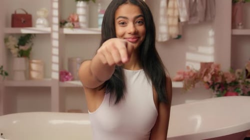 Lateinamerikanische Frau Ethnisches Mädchen im rosa Bonbon-Badezimmer zeigt Hey du Geste Hispanische Frau