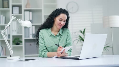 Woman Attending Virtual Meeting, Taking Notes